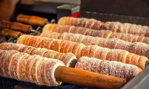 Trdelník, un délicieux dessert tchèque, cuit sur des broches en bois, saupoudré de sucre.