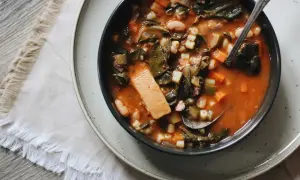 Un bol de ribollita toscana, une soupe épaisse et réconfortante avec des légumes verts, des haricots et des pâtes, servie avec une cuillère.