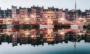 Les maisons colorées de Honfleur se reflètent dans l'eau calme, parfait pour un weekend. Bateaux amarrés, lumières douces.