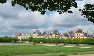 Magnifique vue du château de Fontainebleau, idéal pour visiter. Pelouse verdoyante, fontaine et arbres taillés.