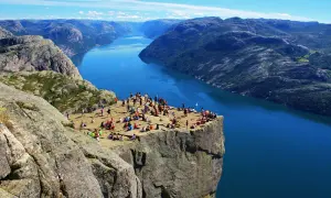 Vue spectaculaire sur un fjord norvégien, avec des randonneurs profitant du paysage. Un souvenir parfait de notre road trip Scandinavie 2 semaines.