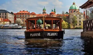 Une croisière à Prague sur le bateau "Plavuně" offre une vue magnifique sur les bâtiments historiques et les dômes verts.