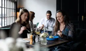 Ambiance chaleureuse pour savoir où manger à Honfleur. Quatre personnes savourent un repas dans un restaurant cosy.