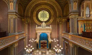 Intérieur orné de la synagogue espagnole de Prague, avec un vitrail circulaire, un Aron Kodesh bleu et des lustres dorés.