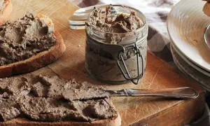 Des toasts tartinés de pâté, prêts à déguster. Un pot de crostini toscani et une assiette de crostini empilés complètent cette scène gourmande.