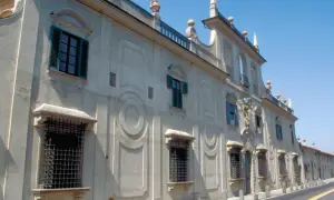 Façade d'une villa à Sesto Fiorentino, avec des fenêtres à volets verts et des ornements circulaires sur le mur.