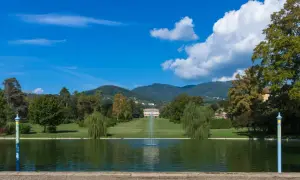 Le parc de la villa reale di Marlia s'étend devant un étang paisible, avec une fontaine jaillissant au centre. Des arbres majestueux bordent la pelouse menant à la villa.
