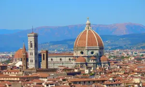 La célèbre coupole de Florence domine la ville, avec son campanile et ses toits de tuiles rouges sous un ciel bleu.