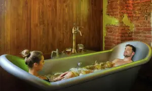 Un couple profite d'un bain bière à Prague, avec des chopes de bière à portée de main.