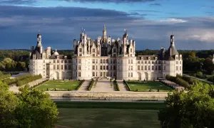 Le majestueux château de Chambord se dresse, avec ses tours et ses toits complexes, sous un ciel dramatique.