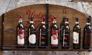 Huit bouteilles de vin, dont plusieurs de **vin de Toscane**, alignées sur une étagère en bois ornée d'une inscription "Vintage".