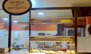 Un comptoir de restaurant à Madrid, avec un panneau "Entrega de Montaditos". Des plats appétissants sont exposés, parfaits pour savoir où manger à Madrid.