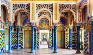 Intérieur du Castello di Sammezzano, une salle aux arcs mauresques, colonnes bleues et motifs géométriques colorés.