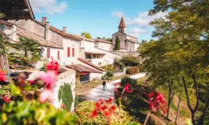 Un homme marche dans un village pittoresque, parmi les plus beaux villages du Tarn-et-Garonne. L'église domine le paysage.