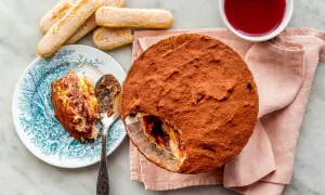 Délicieuse zuppa inglese recette, avec une part déjà servie sur une assiette ornée. Des biscuits à la cuillère et une coupelle de coulis complètent ce dessert gourmand.