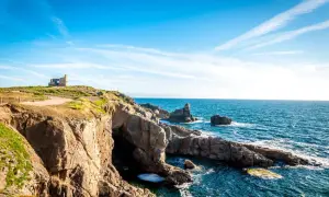 Falaises rocheuses et ruines d'un bâtiment sur une colline surplombant la mer bleue. Idéal pour savoir que faire à Quiberon ce week-end.