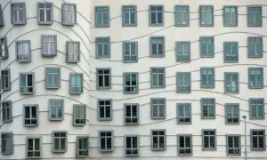 La façade ondulée de la Dancing House à Prague, avec ses fenêtres grises disposées en rangées, semble danser sous le ciel.