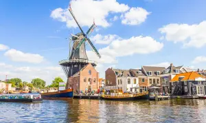 Un moulin à vent historique domine un canal bordé de maisons pittoresques. Une idée de que faire aux Pays-Bas : flâner le long de l'eau.