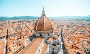 Vue aérienne de Florence, avec le dôme de Brunelleschi dominant la ville. Les toits de tuiles orangées s'étendent à perte de vue.