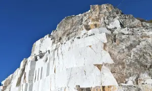 Carrières de marbre blanc à Carrare, Italie, sous un ciel bleu intense. Les blocs taillés révèlent la beauté brute de la roche.