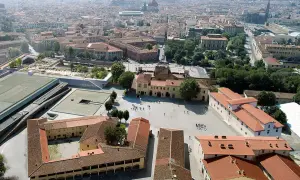 Vue aérienne d'une ville avec des bâtiments historiques et une nouvelle structure moderne, la Fortezza da Basso, ornée de verdure.