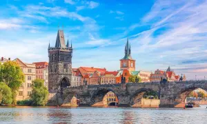 Le pont Charles et la tour de la Vieille Ville, témoins de la riche prague histoire, se reflètent dans la Vltava sous un ciel bleu.