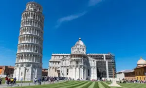 La célèbre tour de Pise, penchée et majestueuse, se dresse fièrement sous un ciel bleu éclatant, à côté de la cathédrale.