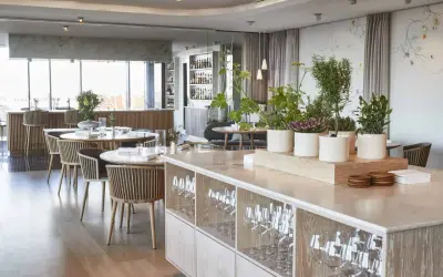 Ambiance élégante d'un restaurant à Copenhague, avec des tables dressées, des plantes et une vue sur le bar. Idéal pour découvrir les meilleurs restaurants Copenhague.