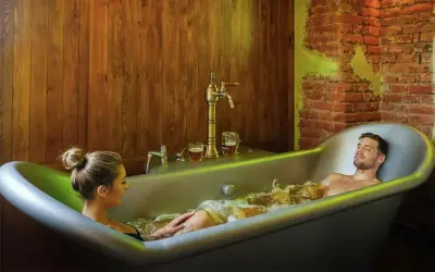 Un couple profite d'un bain bière à Prague, avec des chopes de bière à portée de main.