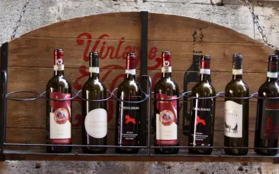 Huit bouteilles de vin, dont plusieurs de **vin de Toscane**, alignées sur une étagère en bois ornée d'une inscription "Vintage".