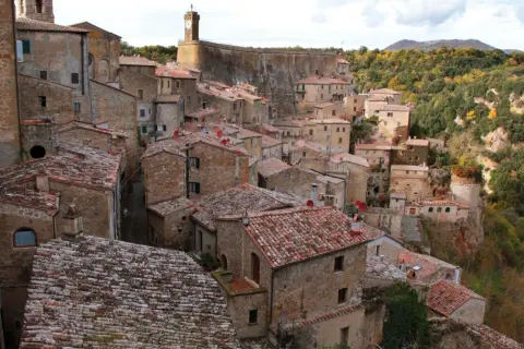 Vue panoramique de Sorano, Italie, un village médiéval perché sur une falaise, avec ses maisons en pierre et ses toits de tuiles rouges.