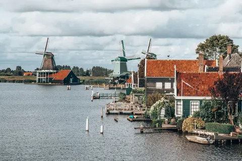Moulins à vent et maisons traditionnelles au bord de l'eau, un paysage typique pour savoir quoi visiter en Hollande.
