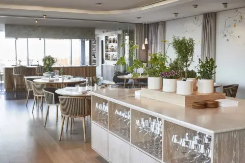 Ambiance élégante d'un restaurant à Copenhague, avec des tables dressées, des plantes et une vue sur le bar. Idéal pour découvrir les meilleurs restaurants Copenhague.