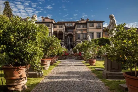 Palazzo Pfanner et son jardin à Lucca, avec des arbres en pot, des statues et une fontaine.