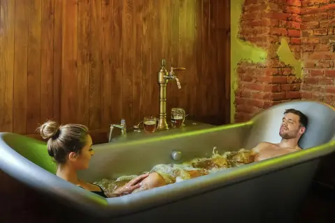 Un couple profite d'un bain bière à Prague, avec des chopes de bière à portée de main.