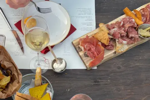 Assiette de charcuterie et de fromage, vin blanc, chips et pain, dans un vignoble de la province de Grosseto.