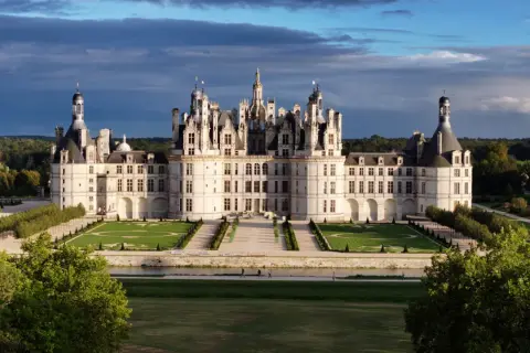 Le majestueux château de Chambord se dresse, avec ses tours et ses toits complexes, sous un ciel dramatique.