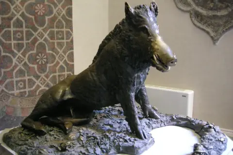 Sculpture d'un sanglier, inspirée par l'art de Florence, posé sur un socle rocheux.