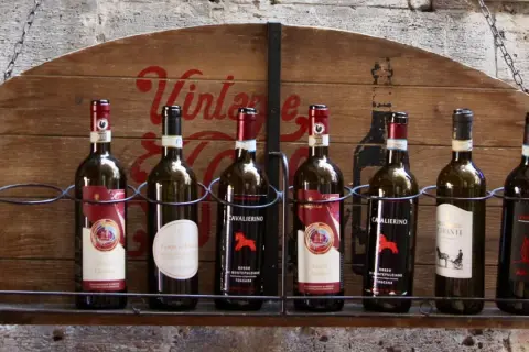 Huit bouteilles de vin, dont plusieurs de **vin de Toscane**, alignées sur une étagère en bois ornée d'une inscription "Vintage".