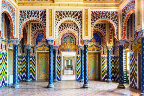 Intérieur du Castello di Sammezzano, une salle aux arcs mauresques, colonnes bleues et motifs géométriques colorés.