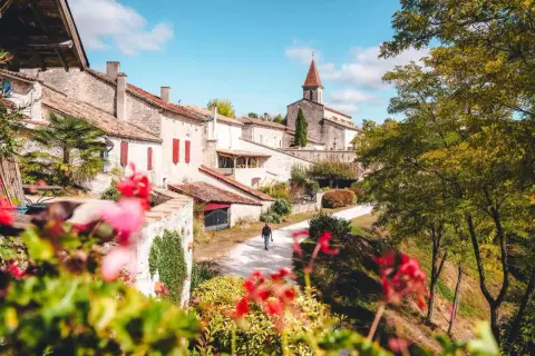 Un homme marche dans un village pittoresque, parmi les plus beaux villages du Tarn-et-Garonne. L'église domine le paysage.