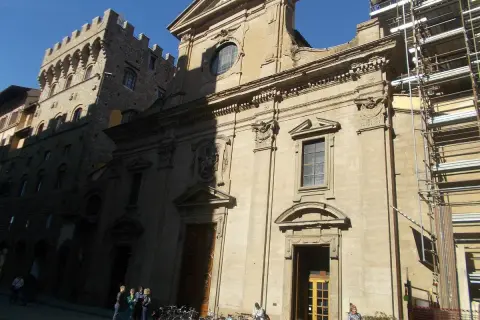 Façade de la basilique Santa Trinita à Florence, avec des échafaudages sur le côté droit. Des vélos sont garés devant.