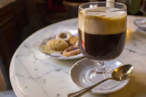 Un café viennois et des biscuits sur une table en marbre, une invitation à découvrir où manger à Turin.