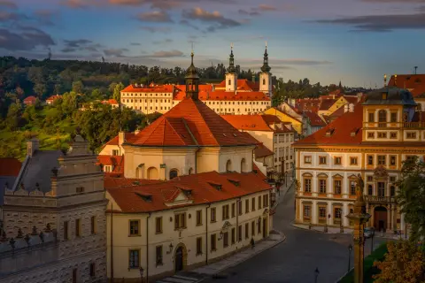 Vue panoramique de Prague au coucher du soleil, avec les toits rouges et les tours du monastère de Strahov dominant le paysage.