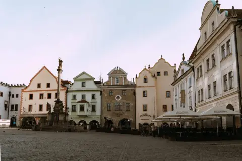 Place de la ville pavée avec une colonne baroque et des maisons colorées, parfait pour visiter la République Tchèque.
