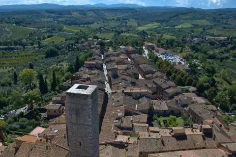 Vue aérienne de Panzano in Chianti, un village toscan pittoresque avec des toits de tuiles, des vignobles et des oliveraies verdoyantes.