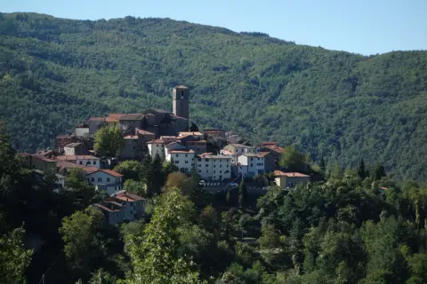 Village de San Marcello Pistoiese niché sur une colline verdoyante, avec son clocher dominant les toits de tuiles rouges.