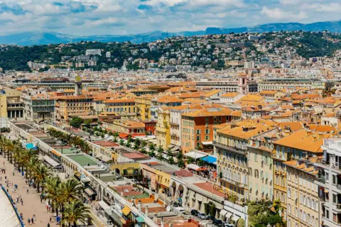 Vue panoramique de Nice, avec ses toits orangés et la colline verdoyante en arrière-plan. Parfait pour un week-end nice.