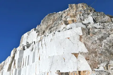 Carrières de marbre blanc à Carrare, Italie, sous un ciel bleu intense. Les blocs taillés révèlent la beauté brute de la roche.
