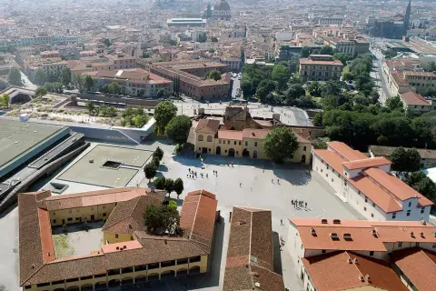 Vue aérienne d'une ville avec des bâtiments historiques et une nouvelle structure moderne, la Fortezza da Basso, ornée de verdure.
